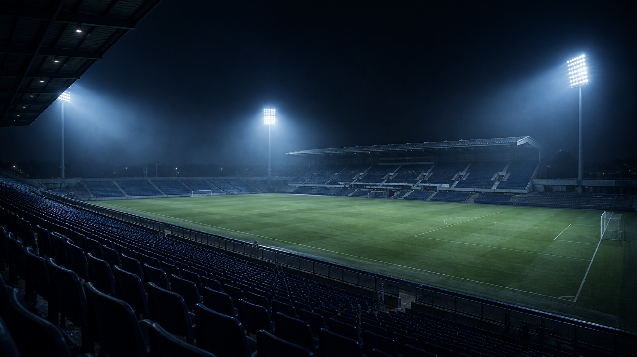 An illuminated football stadium at night under spotlights.