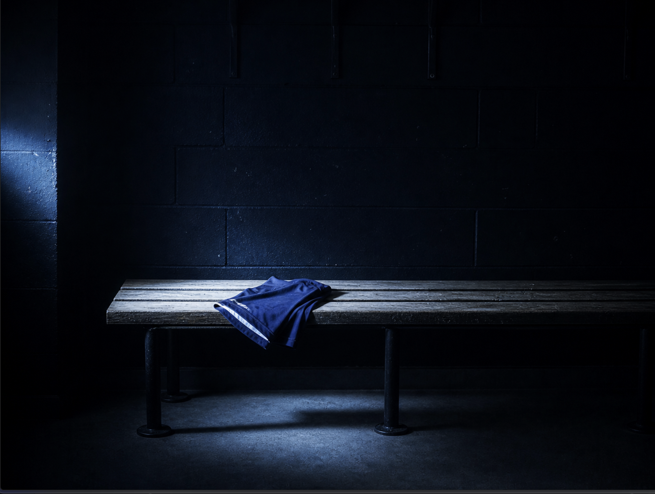 An empty changing-room bench, dim side light, a single folded jersey resting on it. The moment after testimony.